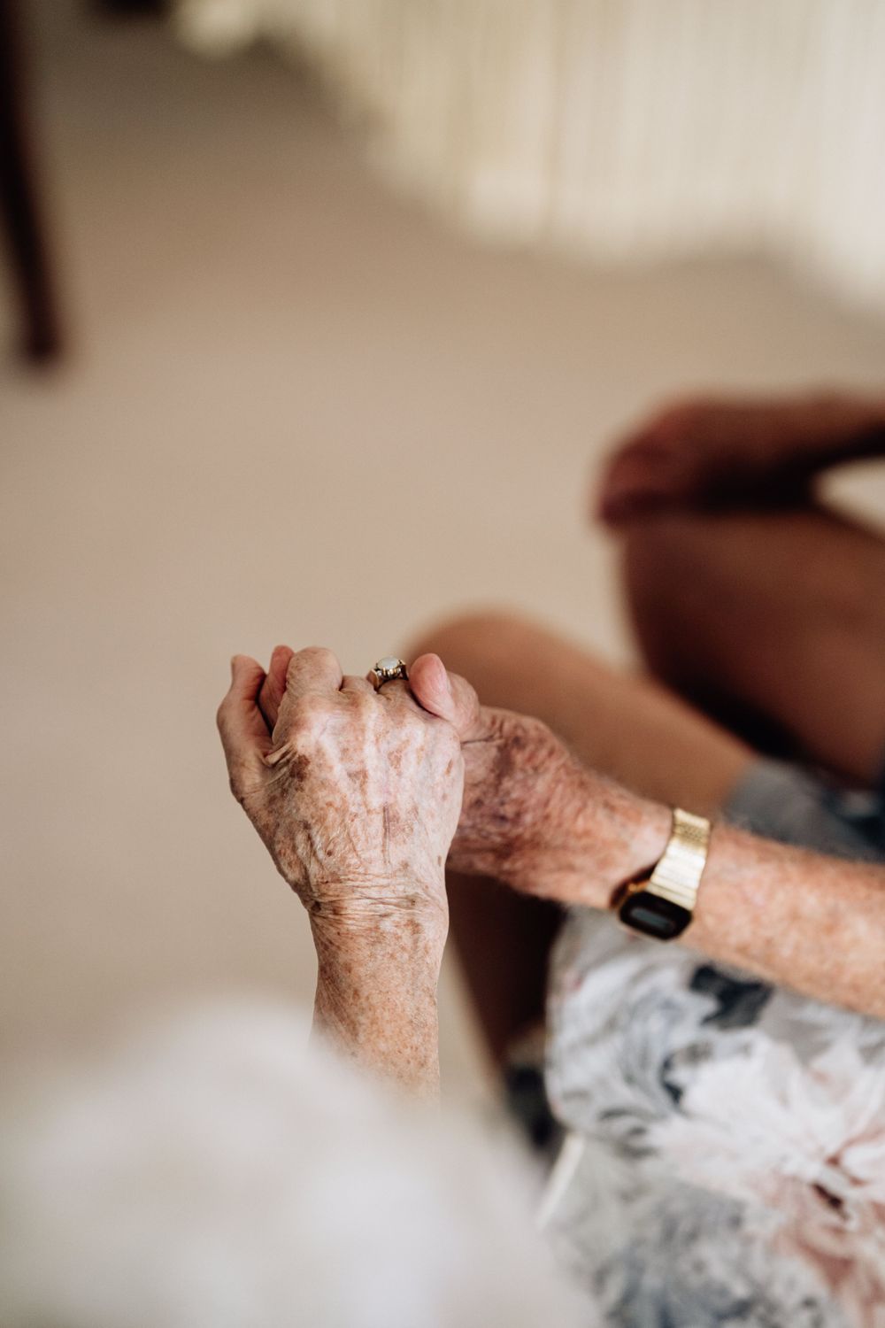 Two hands held together, one of an elderly man and one of an elderly woman.