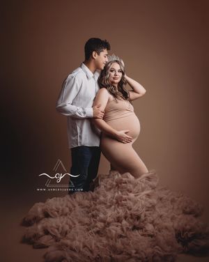 Maternity photo session featuring a couple in warm brown tones with flowing fabric creating a dreamy atmosphere.