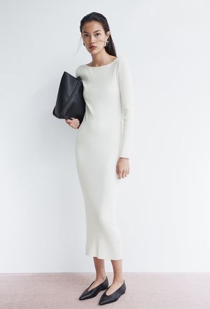 Minimalist white knit dress paired with black clutch and heels in studio setting.