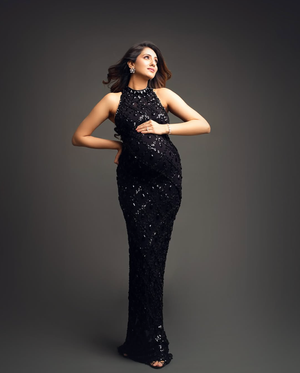 Elegant black sequined gown photographed against dark grey studio backdrop.