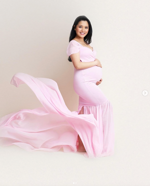 Maternity portrait series with billowing pink dress against white backdrop.