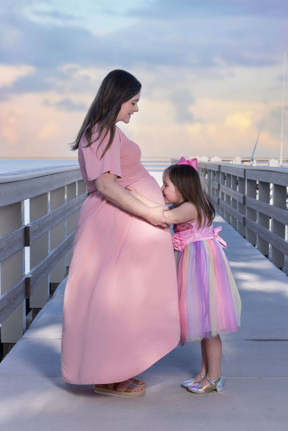 Big sister kissing mom's pregnant belly