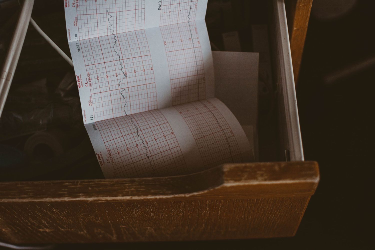 Medical chart printout sitting in wooden holder showing vital sign readings.
