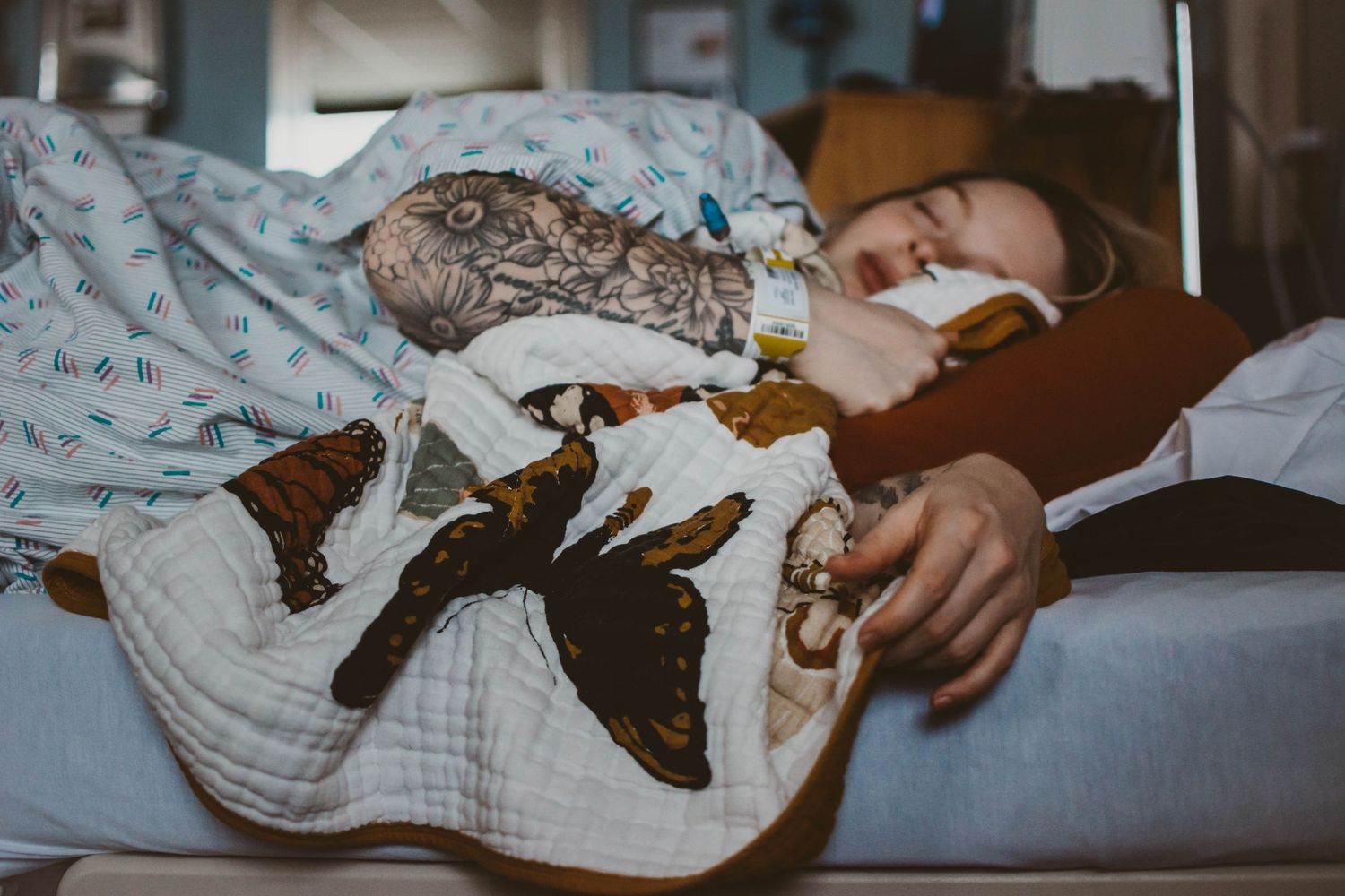 Hospital bed with patterned blankets in low lighting.