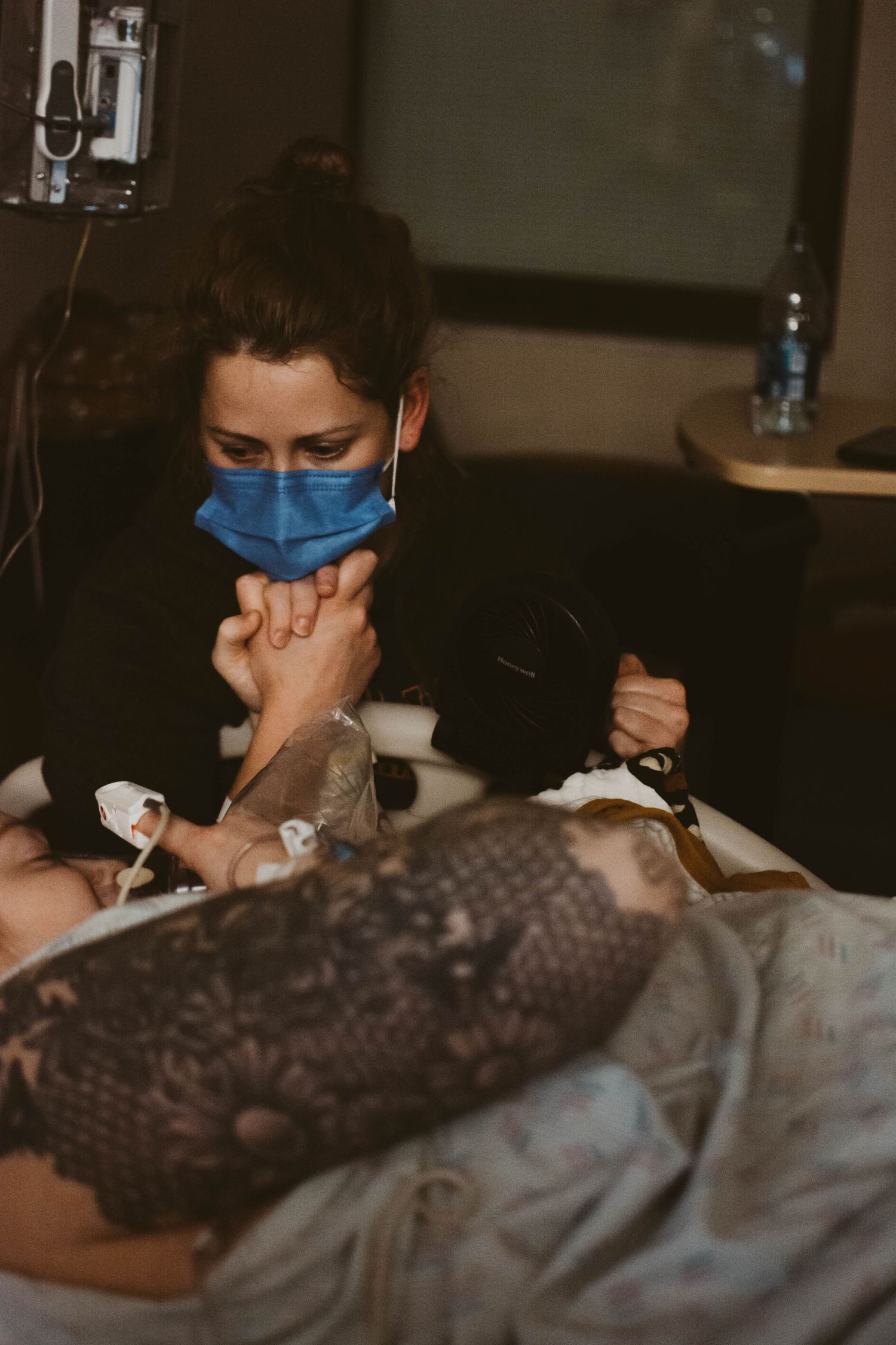 Medical staff wearing protective mask attending to patient in hospital setting.
