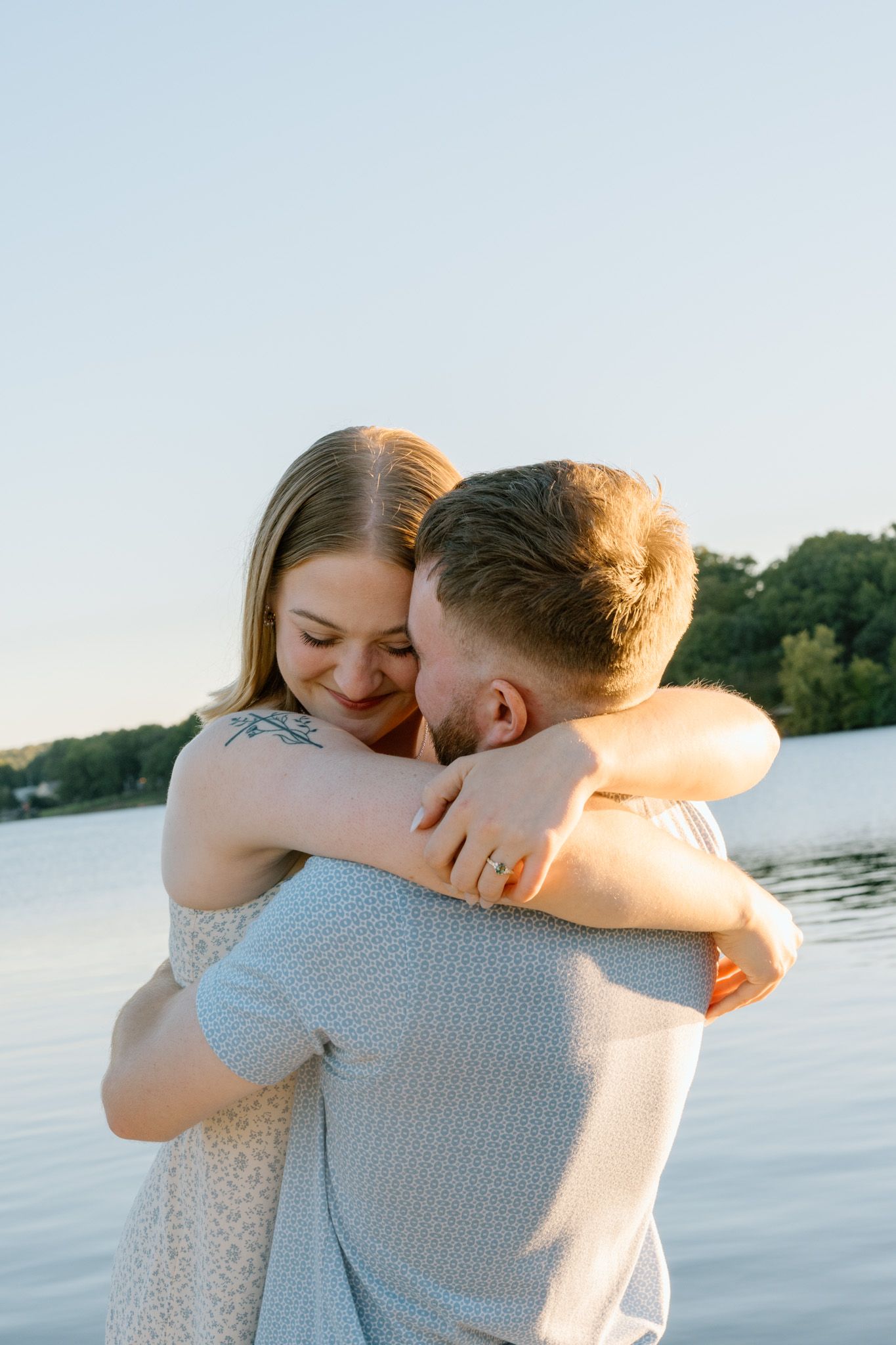 Engaged couple hugging closely during a lakeside sunset engagement session in Northwest Arkansas