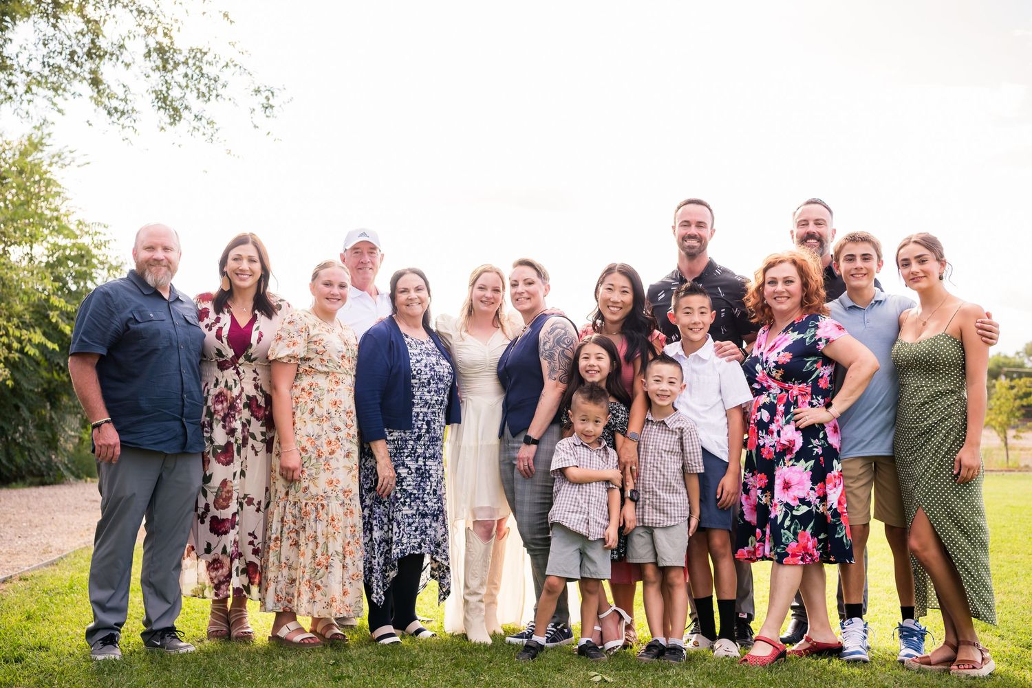 Extended family and friends gather for a group photo outdoors in summer attire.