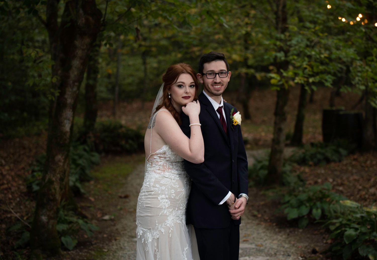 Wedding couple walks together on forest path in soft evening light.