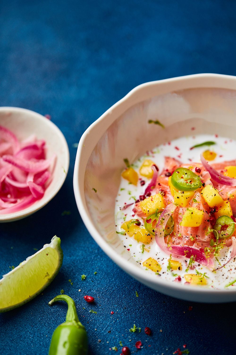Thai-inspired rice bowl with mango, pickled onions, and lime on a dark blue background.