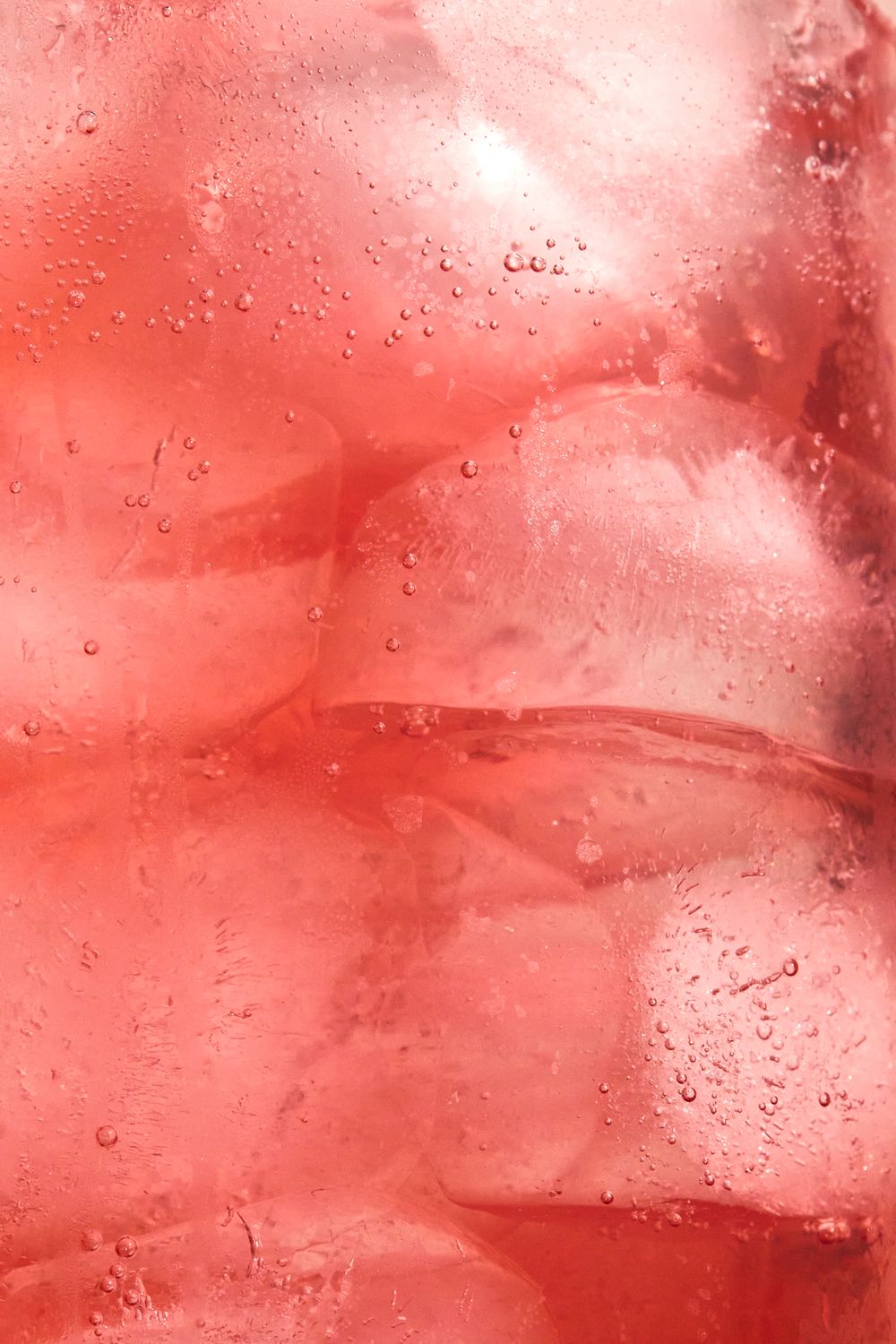 Macro shot of water droplets on pink-tinted glass surface with light filtering through.