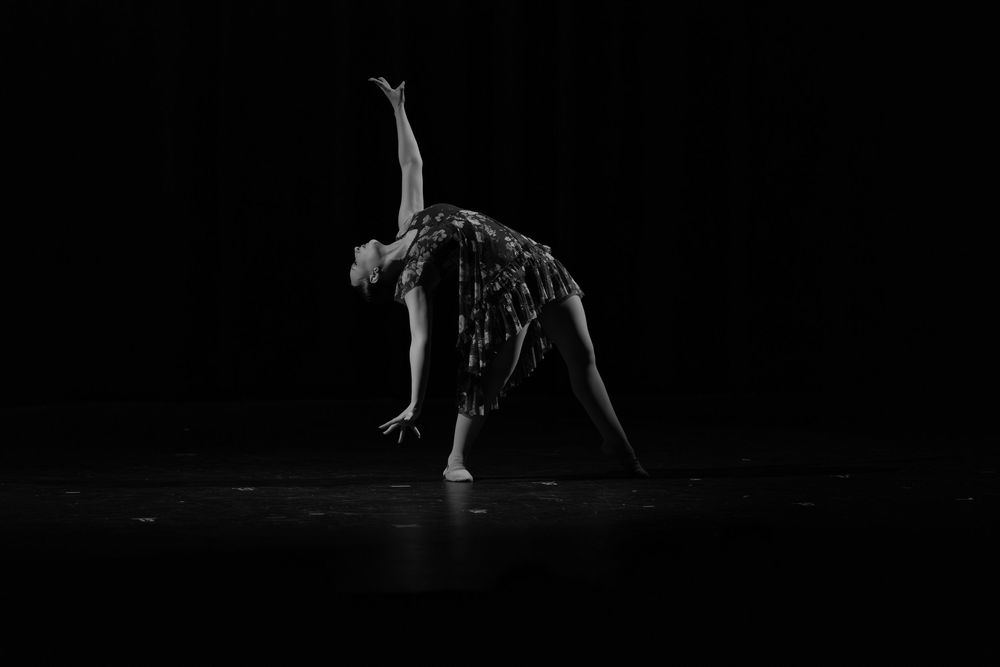 A series of black and white photographs showing dancers performing dynamic moves and stretches in low light.