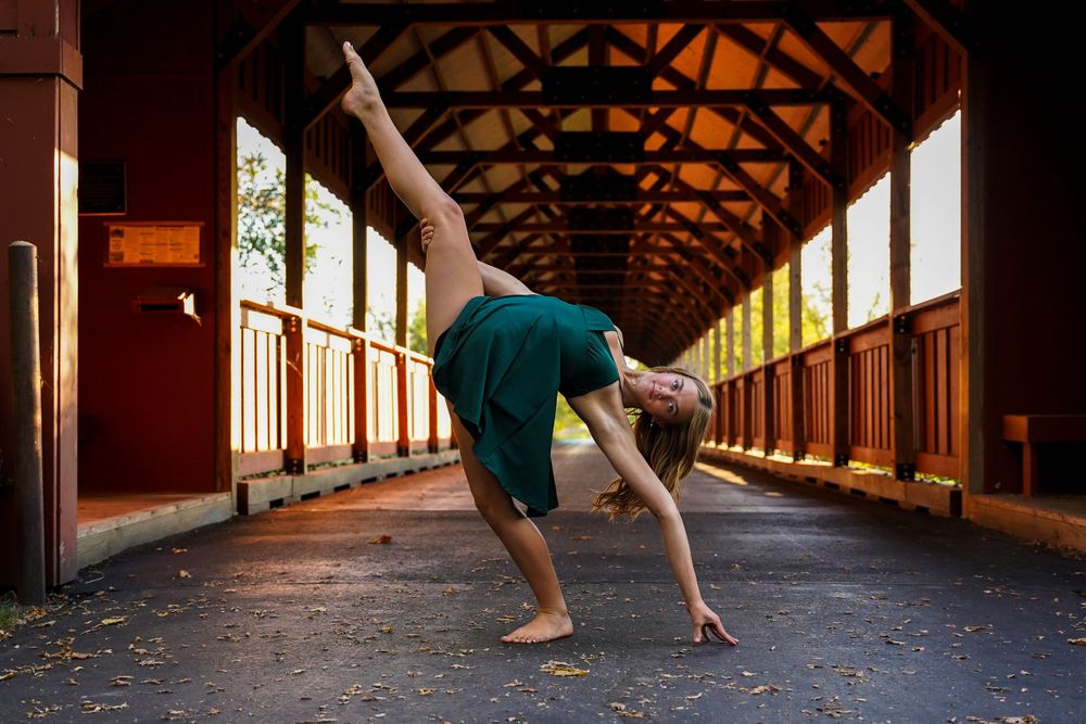 Contemporary dance poses demonstrated in wooden covered bridge interior.