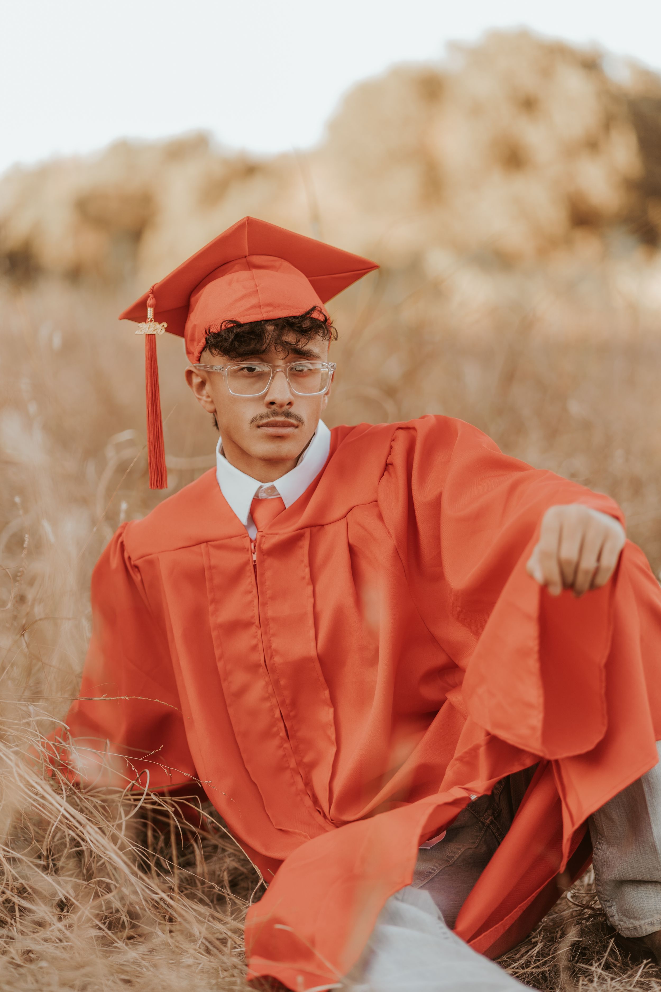 Red graduation gown draped artistically in a field during golden hour.