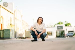 Casual outdoor photo session with person sitting on stone ledge at sunset.