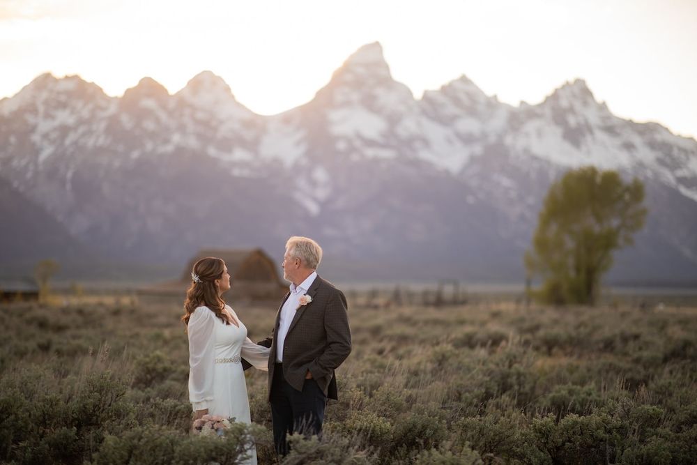 A couple shares an intimate moment at sunset in front of the majestic Grand Teton mountain range in Wyoming.