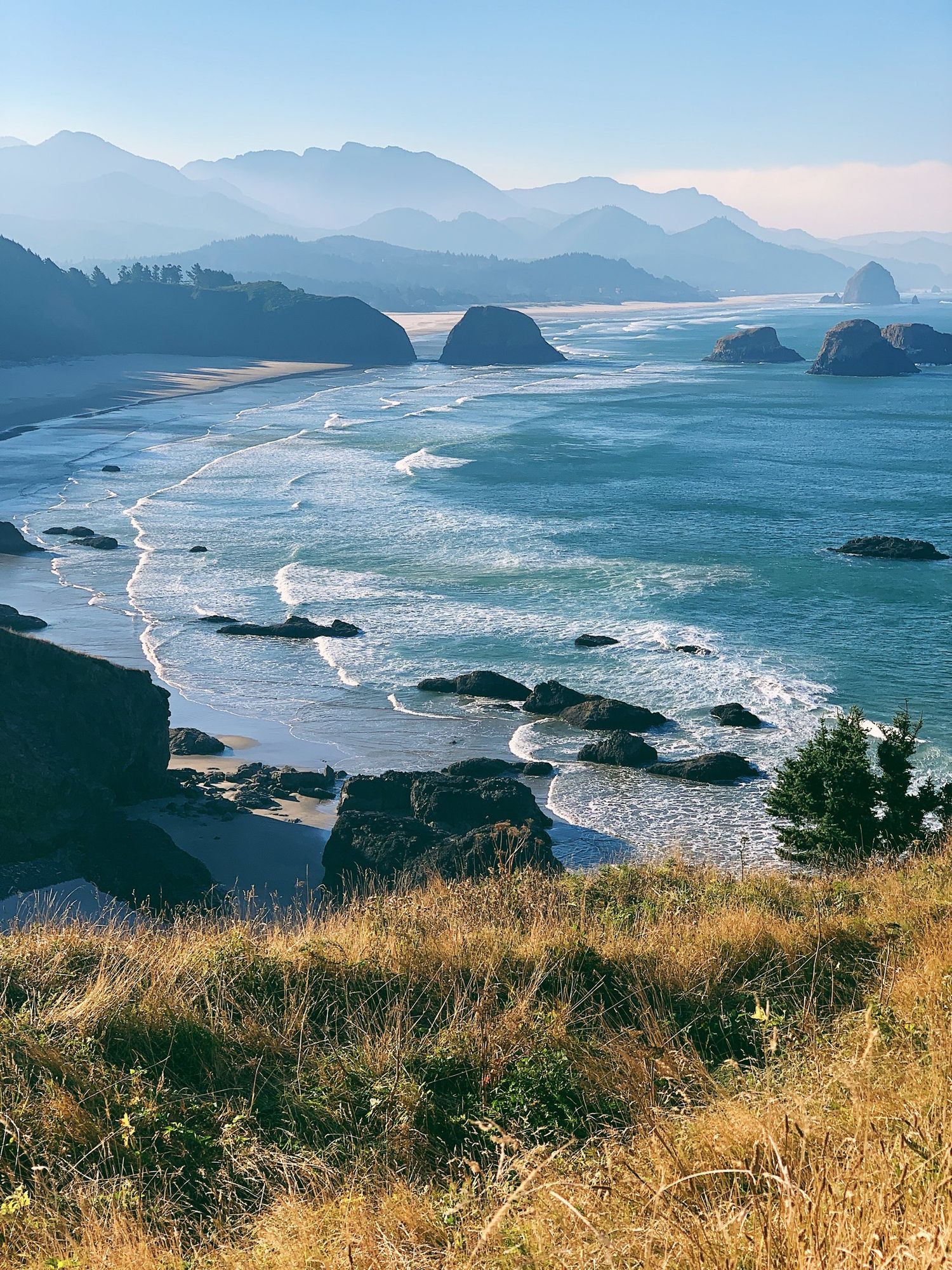 Dramatic coastal landscape with mountains, sea stacks and crashing waves along the Pacific coast.