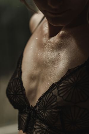 Intimate portrait showing delicate black lace details with water droplets on skin.