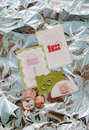 Wedding gift cards and rings arranged on crinkled metallic silver paper background.