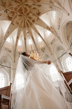 Elegant cathedral interior with ornate vaulted ceilings, chandeliers and flowing white wedding veil.