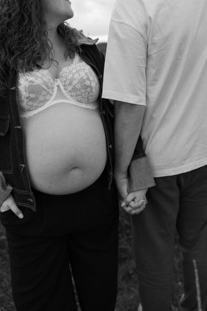 Close-up details of a couple holding hands during an outdoor maternity session.