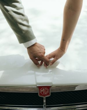 Close-up detail shot of hands touching the emblem on a luxury car.