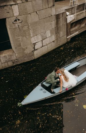 Aerial view of a couple lying in white boats along a stone wall canal.