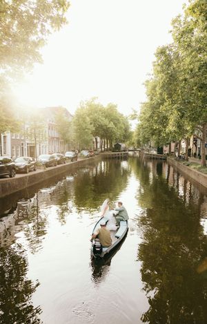 Scenic canal in Amsterdam with gondolas gliding through tree-lined waterways at sunset.