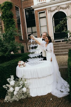 Wedding celebration with champagne tower and flowing white dress against historic building backdrop.