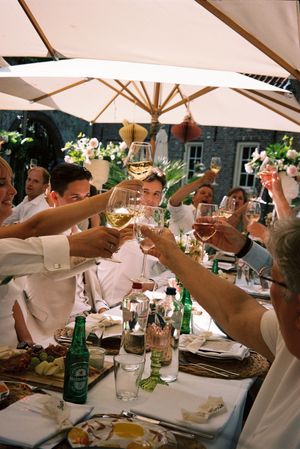 Wedding reception guests raising glasses in a toast under outdoor umbrellas.
