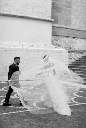 Long flowing bridal veil trailing dramatically across stone steps in black and white.