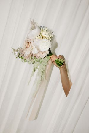Delicate pink and white wedding bouquets with ribbons arranged in sequence against a white backdrop.