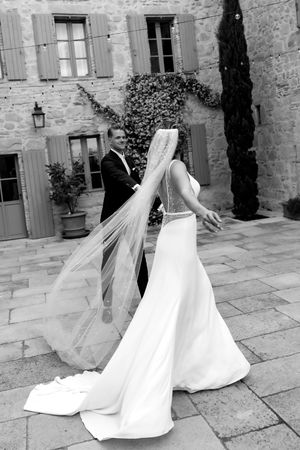 Elegant wedding dress train flowing across stone courtyard in black and white.