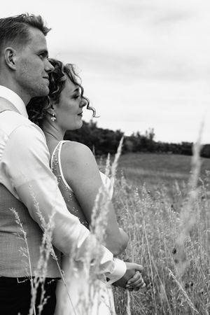Romantic black and white portrait of a couple embracing in a field of tall grass.
