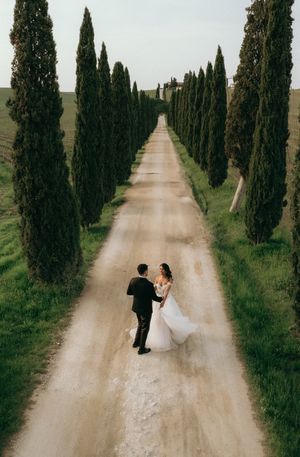 Couple walking down iconic cypress tree-lined road in Tuscany.