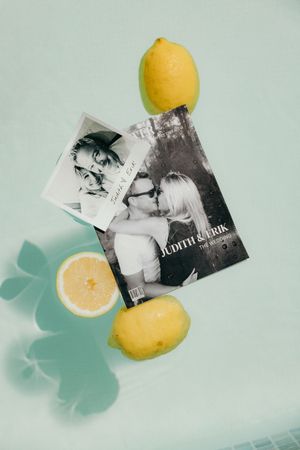 Fresh yellow lemons arranged with black and white photographs on a mint green background.