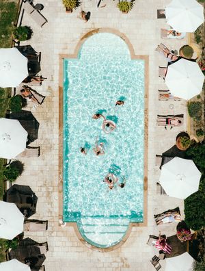 Aerial view of a turquoise swimming pool with people lounging around the edges.