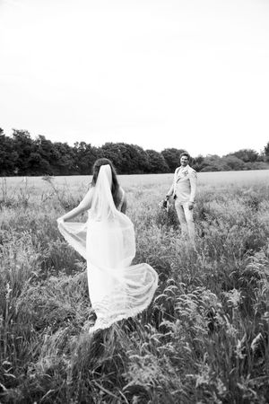 Ethereal black and white photo of bride's veil flowing in a meadow.