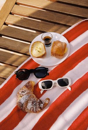 Sunglasses and pastries arranged on a red and white striped surface.