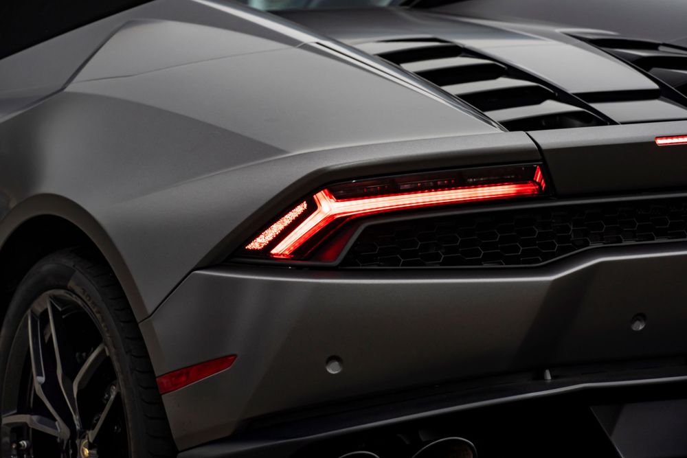 Rear tail light detail of a matte gray Lamborghini Huracan with red LED accents.