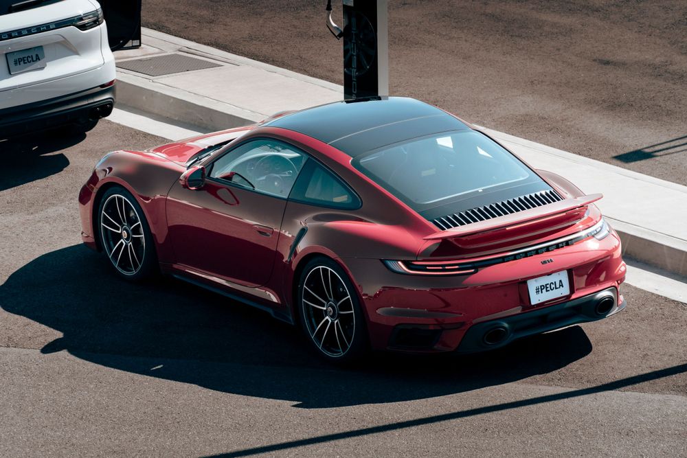 Red Porsche 911 Turbo coupe photographed from above at a sunny intersection showing its sleek roofline.