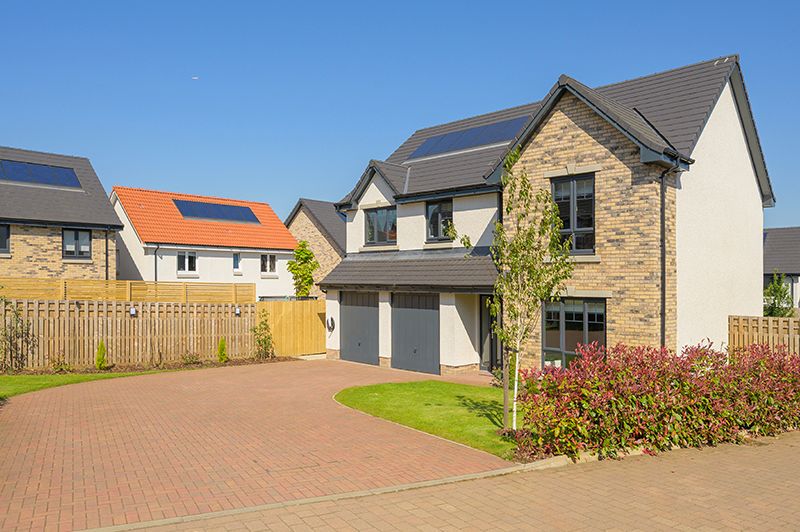 Modern residential homes with driveways and garages line a newly developed suburban neighborhood street.
