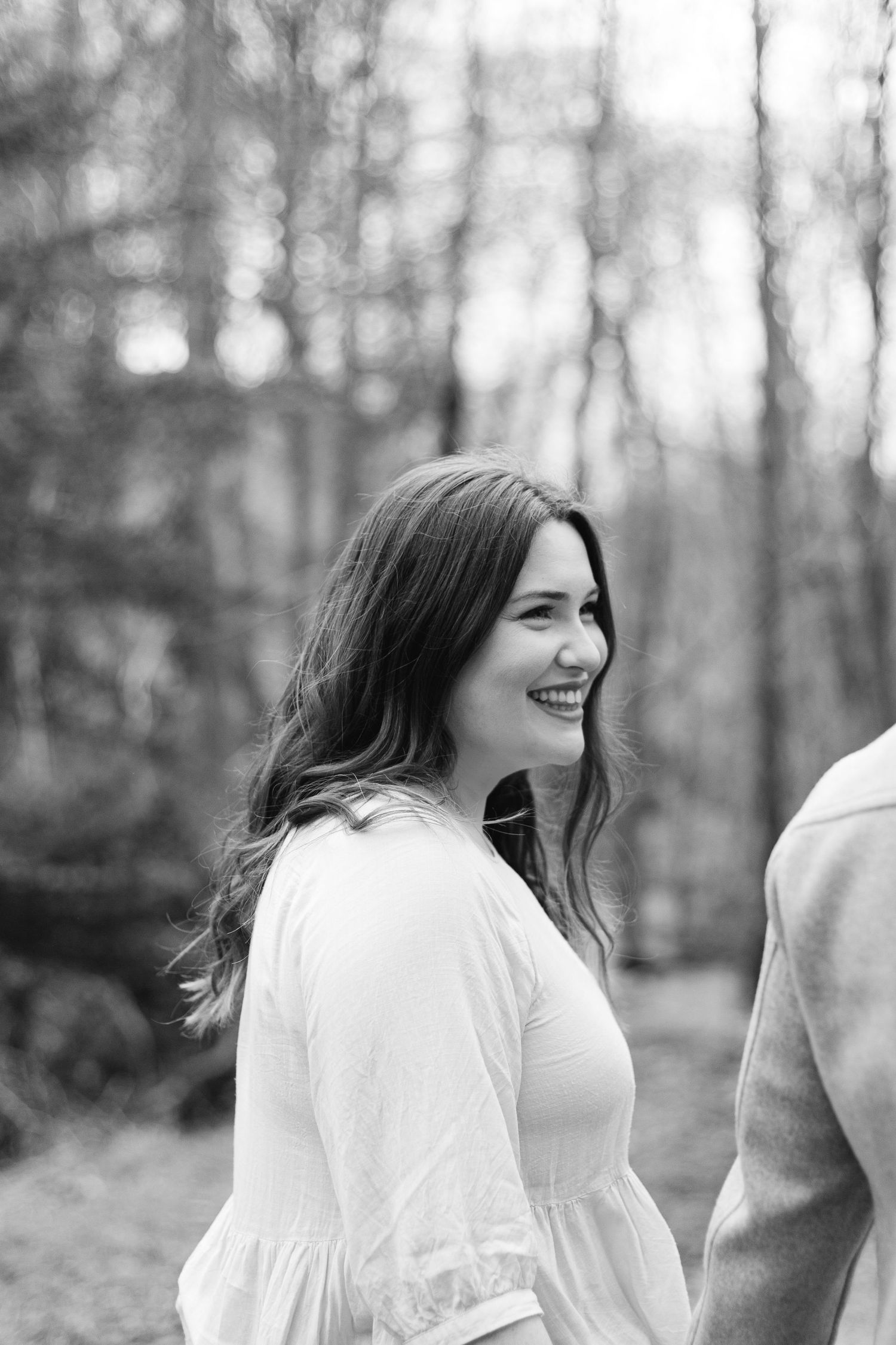 A series of candid black and white photographs showing joyful expressions and genuine laughter in a wooded setting.