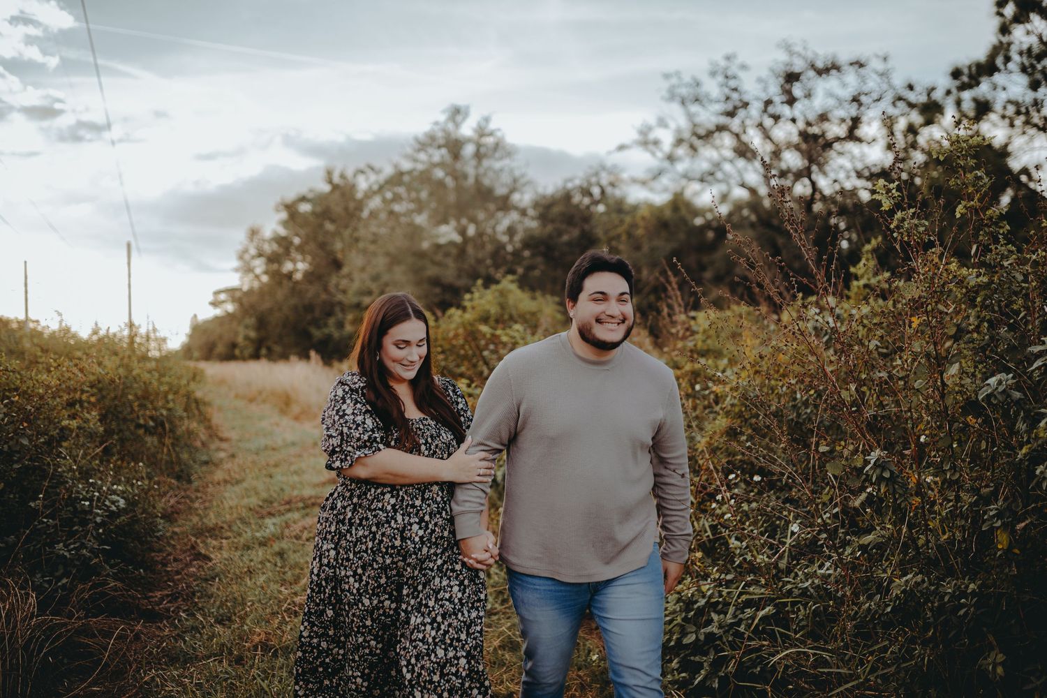 Couple walking and laughing together on nature path surrounded by autumn foliage.
