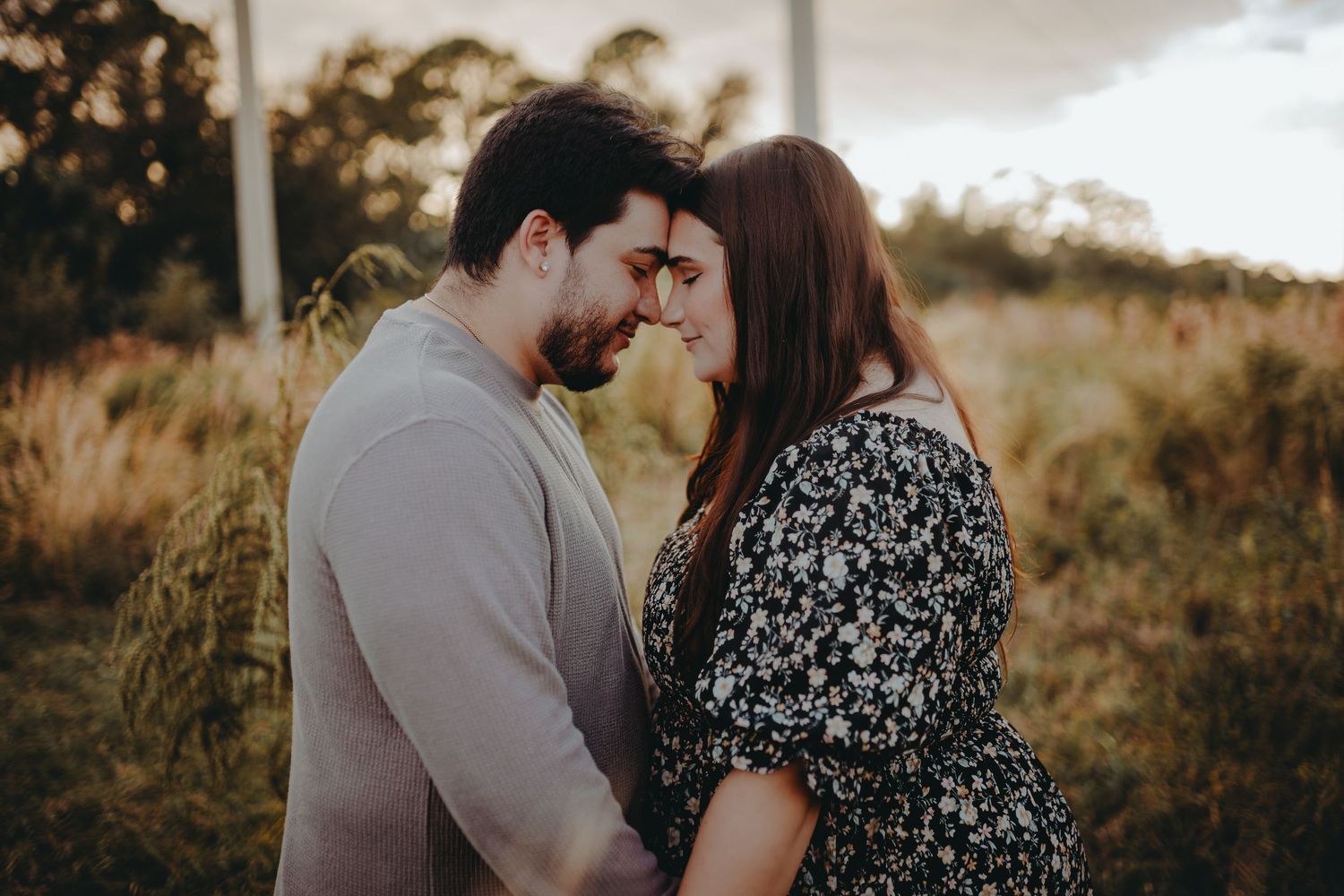 Romantic close-up portrait of couple in matching outfits against golden hour backdrop.
