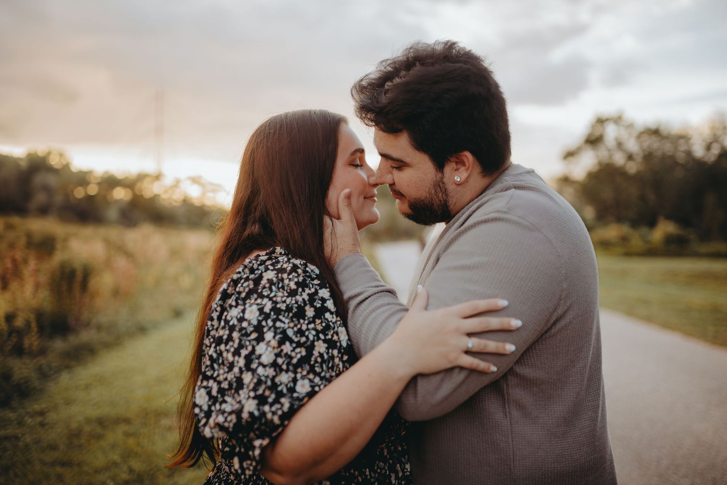 An intimate couple sharing a tender moment on a path at golden hour.