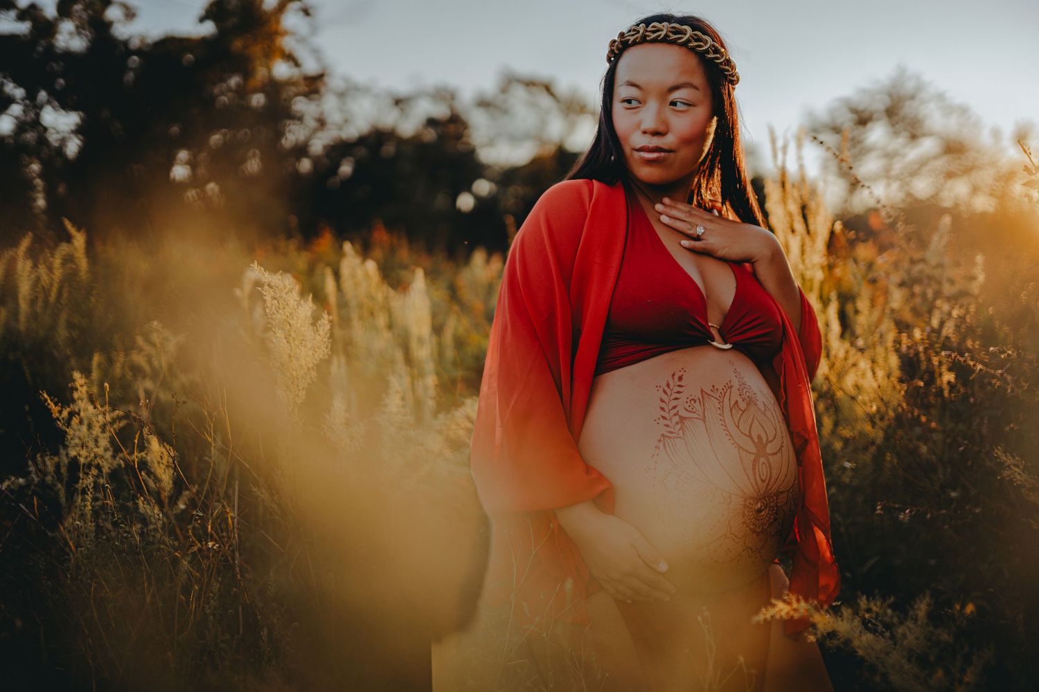An ethereal maternity portrait with golden light filtering through tall grass.