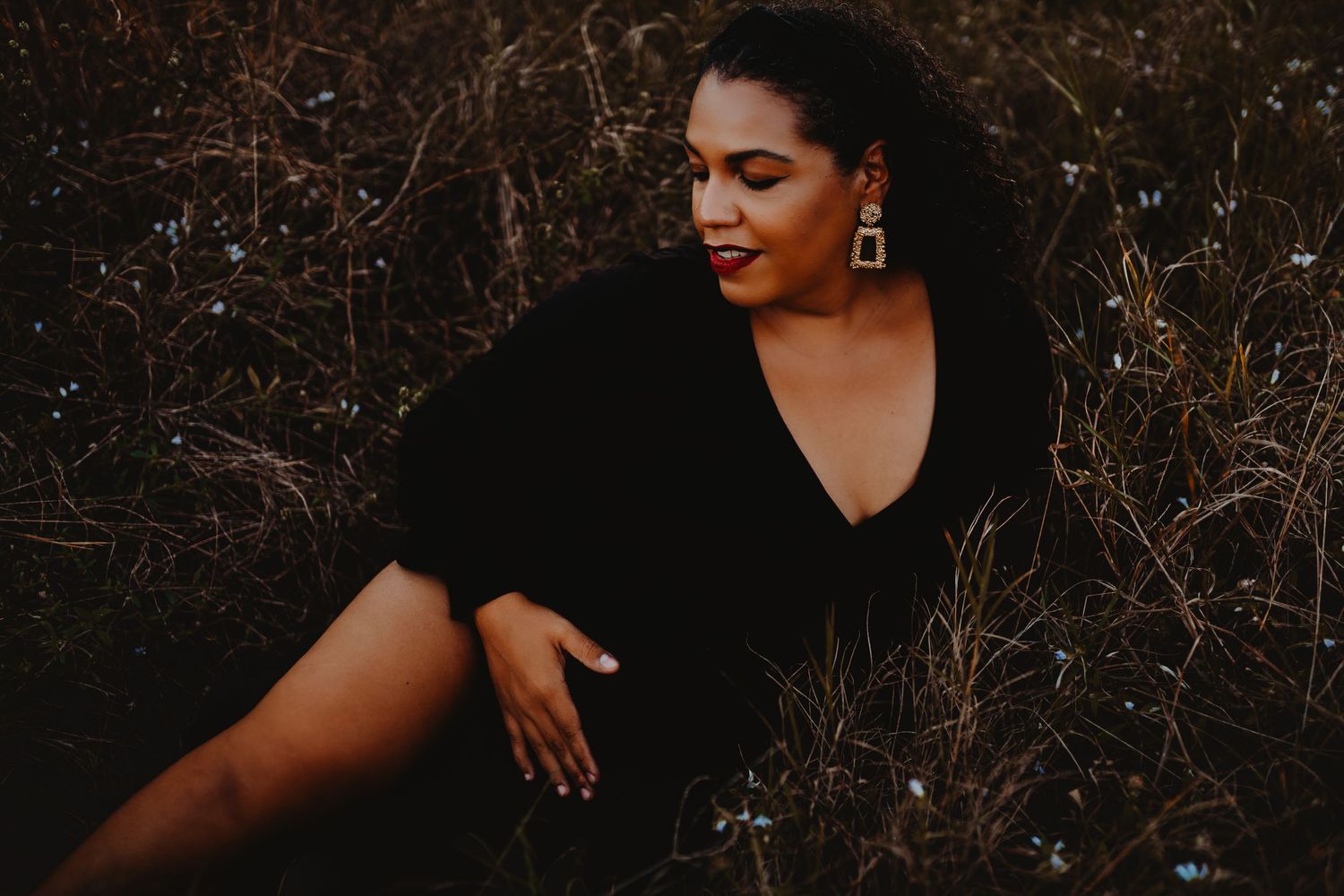 A portrait of someone in a black dress against a natural backdrop.