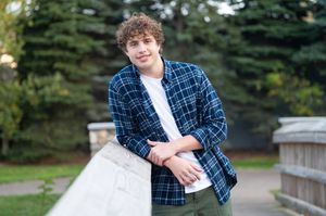 Multiple shots of someone wearing a navy plaid button-down shirt posing outdoors with evergreen trees in the background.