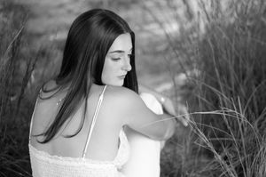 A black and white photo series shows a person in nature wearing a sleeveless top with long dark hair.