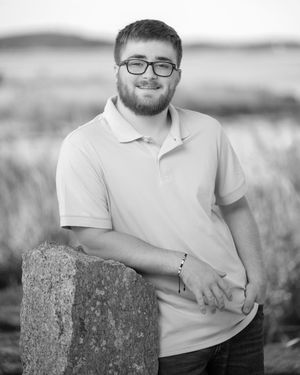 Black and white portrait series showing someone sitting on a stone wall in a field with mountains in the background.